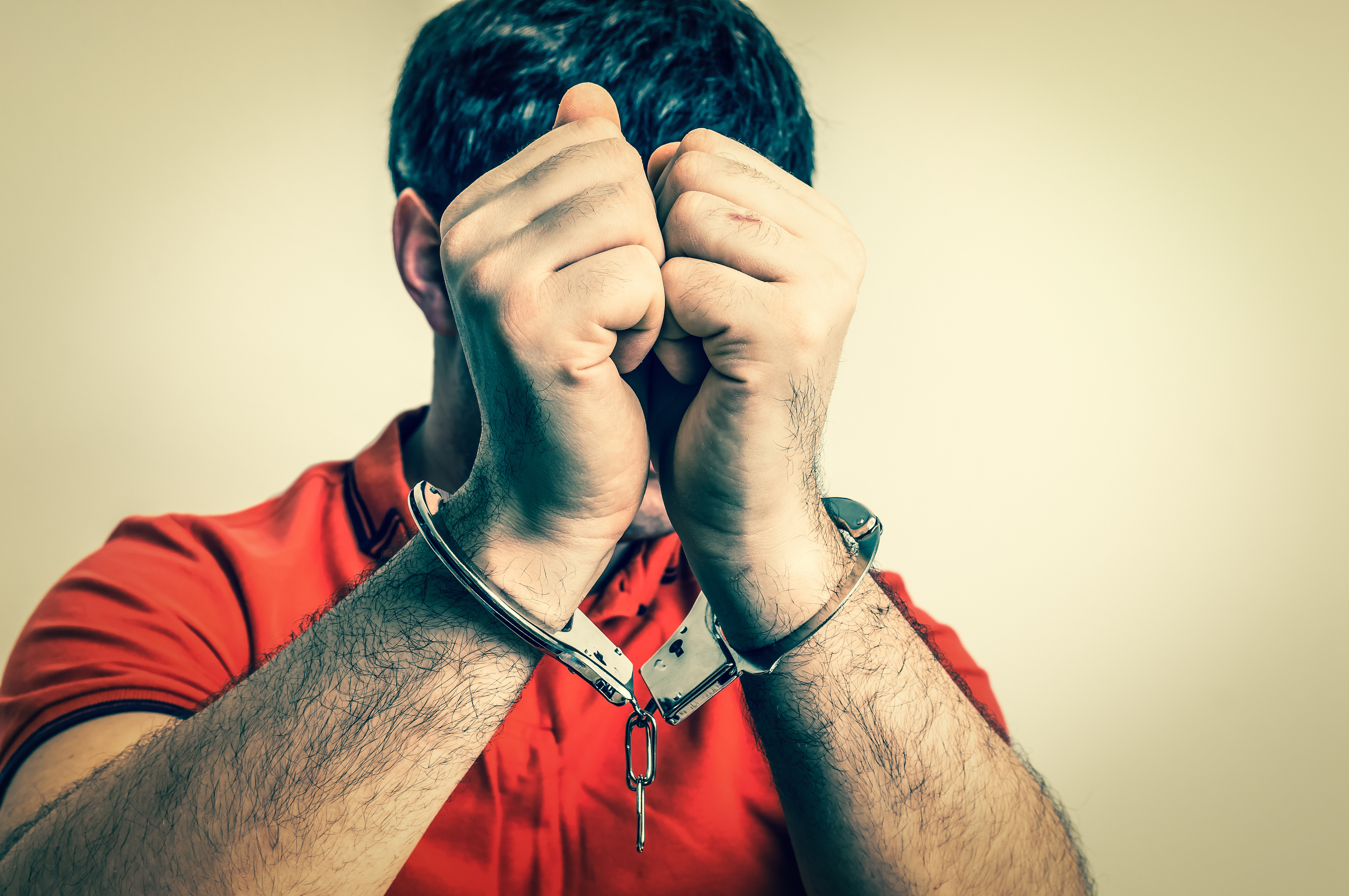 Arrested man in handcuffs hidden his face