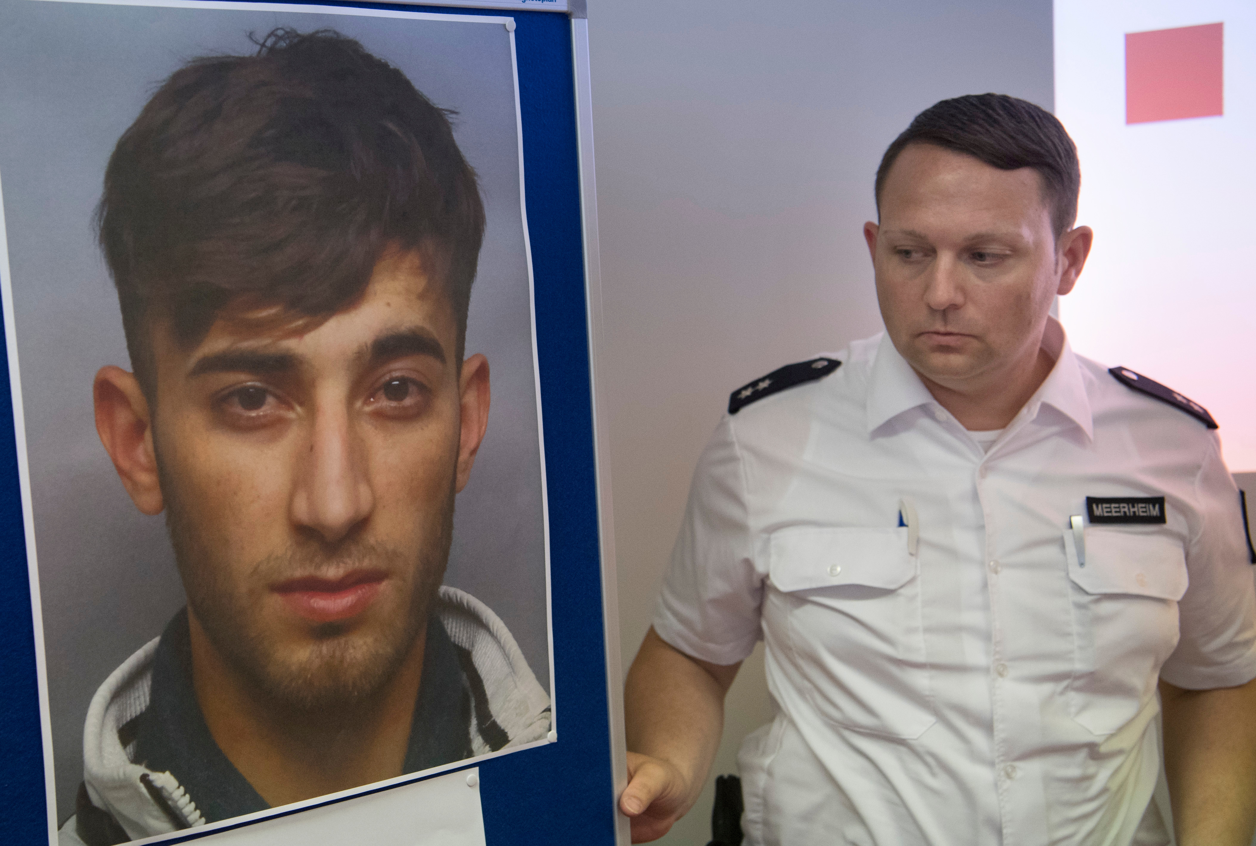 Polizist zeigt Stellwand mit Fahndungsfoto von Ali Bashar