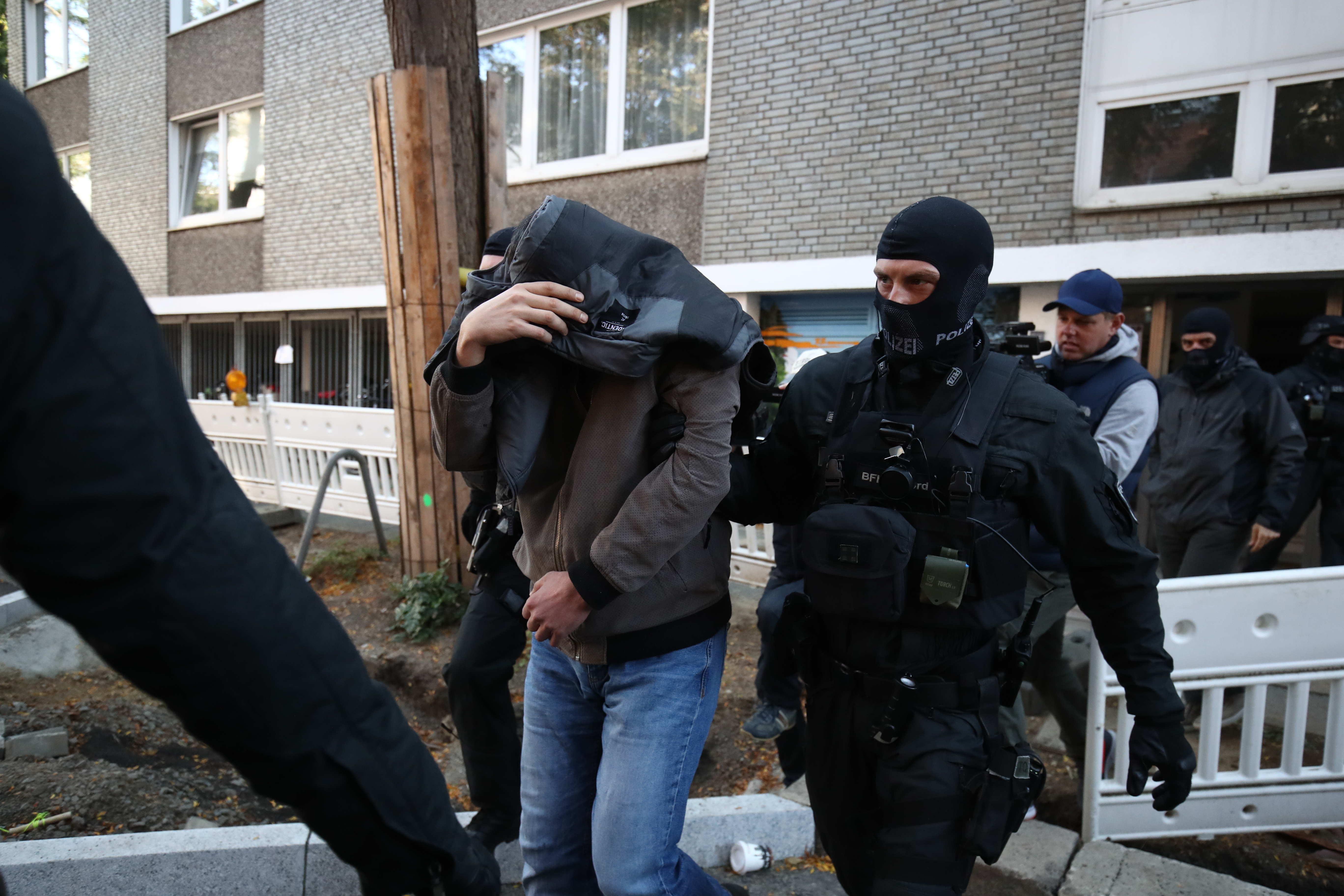 11.09.2019: Razzien wegen Terror-Verdachts in Hamburg. Bild: Ein Mann wird von Polizisten aus einem Haus geführt.
